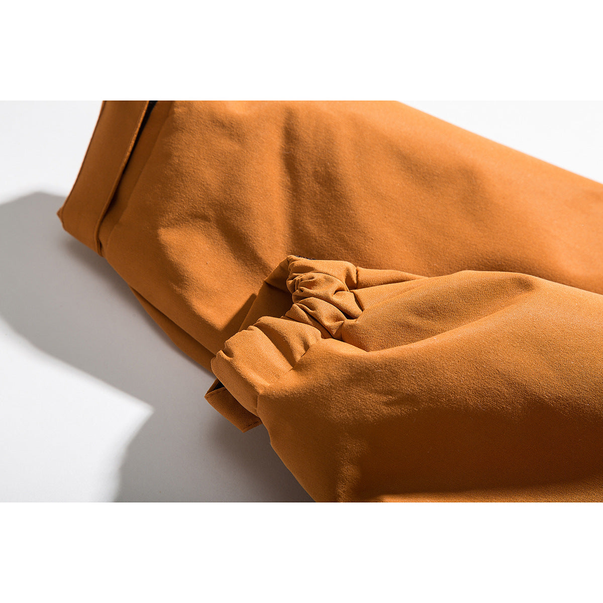 Close-up of an orange jacket sleeve and gathered elastic cuff.