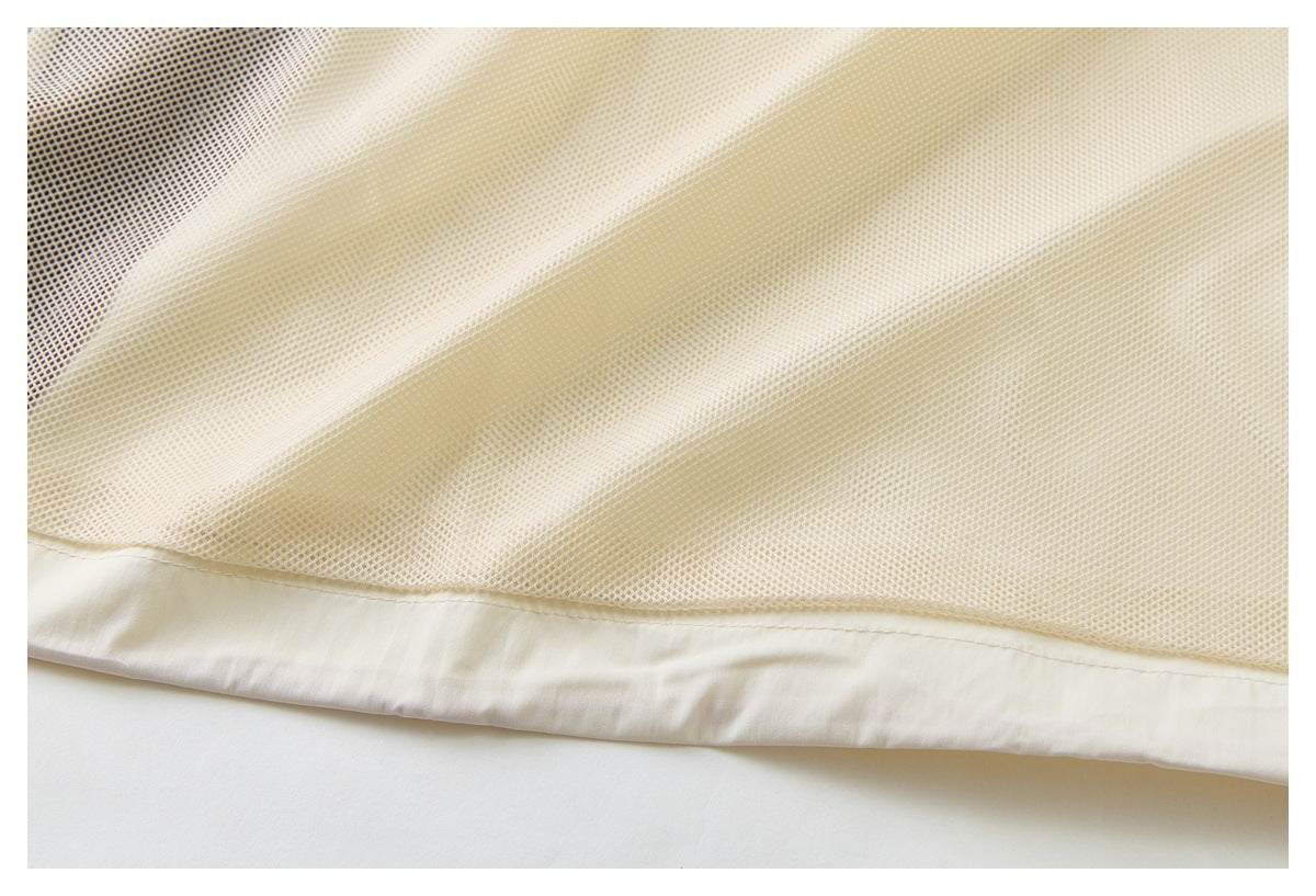 Close-up of ivory mesh fabric joined to a smooth folded hem.