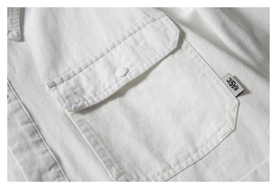 Close-up of a white shirt’s flap chest pocket, snap button and small sewn label.