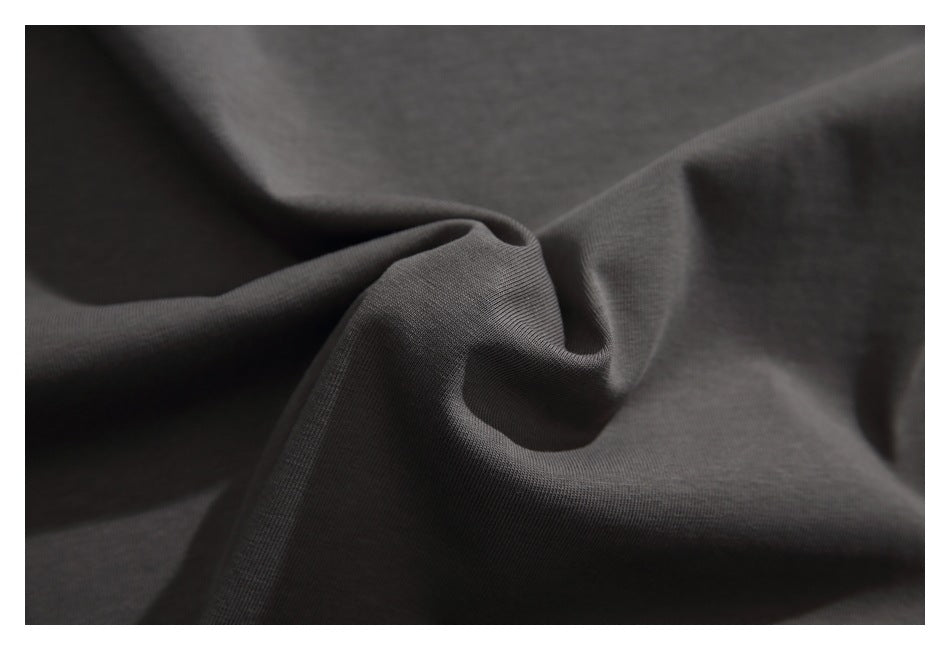 Extreme close-up of charcoal garment fabric gathered into folds, showing its surface texture.