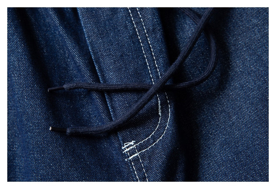 Close-up of dark indigo denim shorts showing a dark drawstring crossing over the waistband seam.