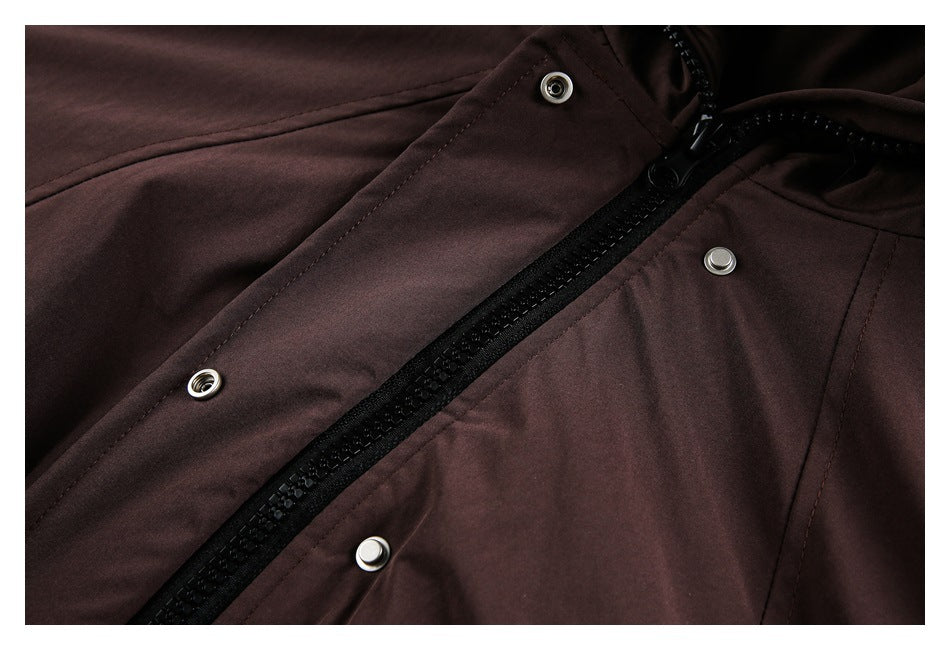 Close-up of a dark brown jacket's black front zipper and silver snap fasteners.