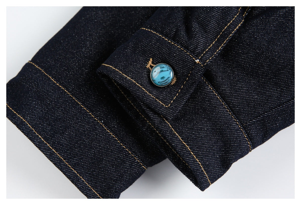 Close-up of a turquoise button on a stitched dark denim tab.