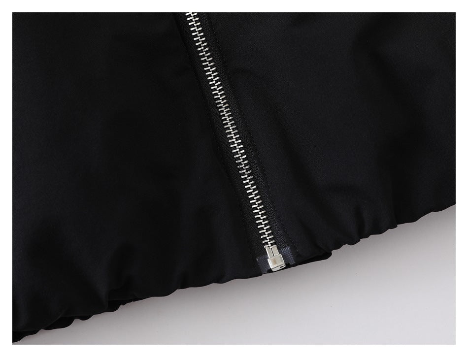 Close-up of the silver zipper end and gathered elasticized hem on the black jacket.