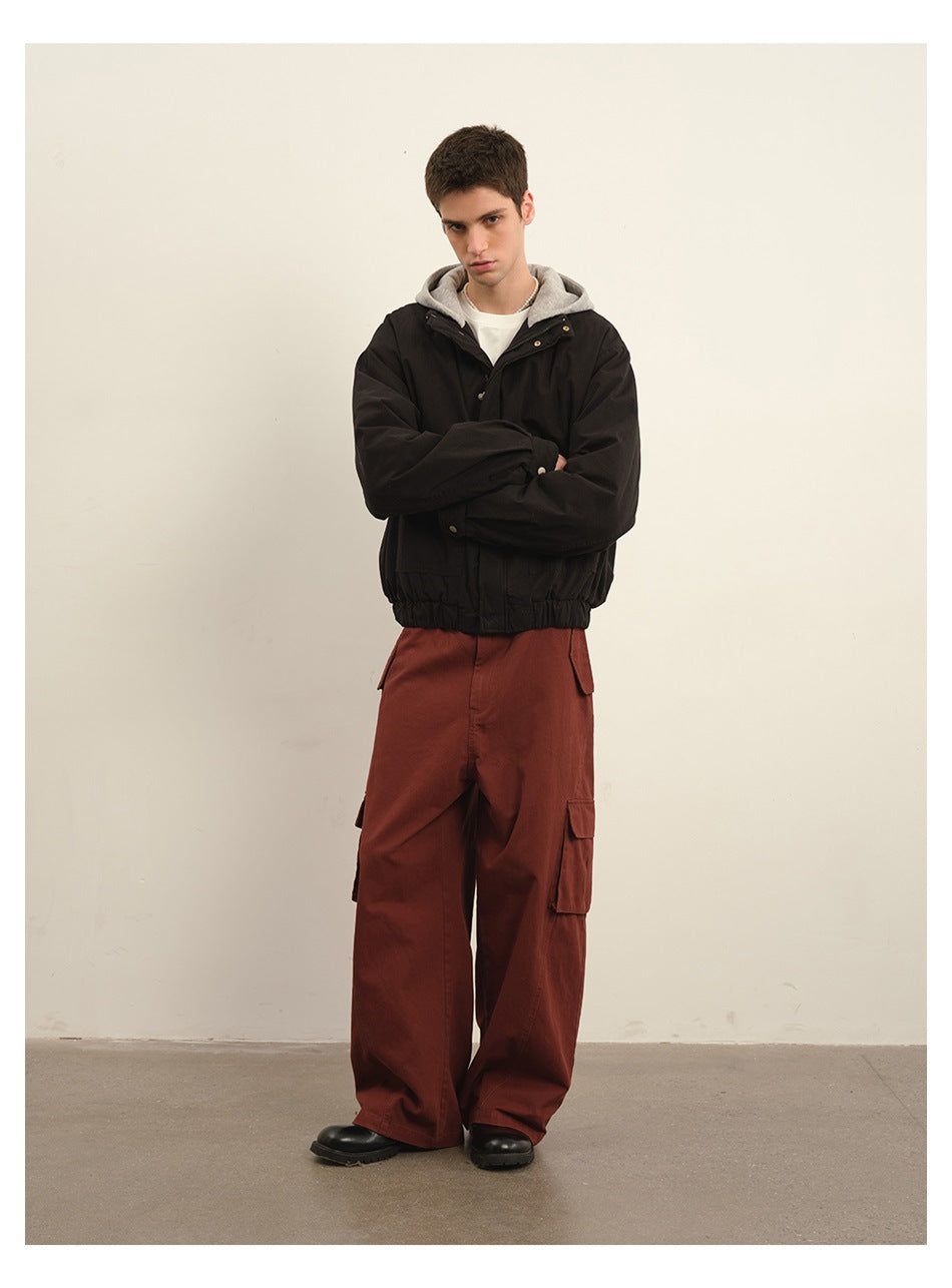 Model wearing a black hooded jacket with flap pockets and rust cargo pants.