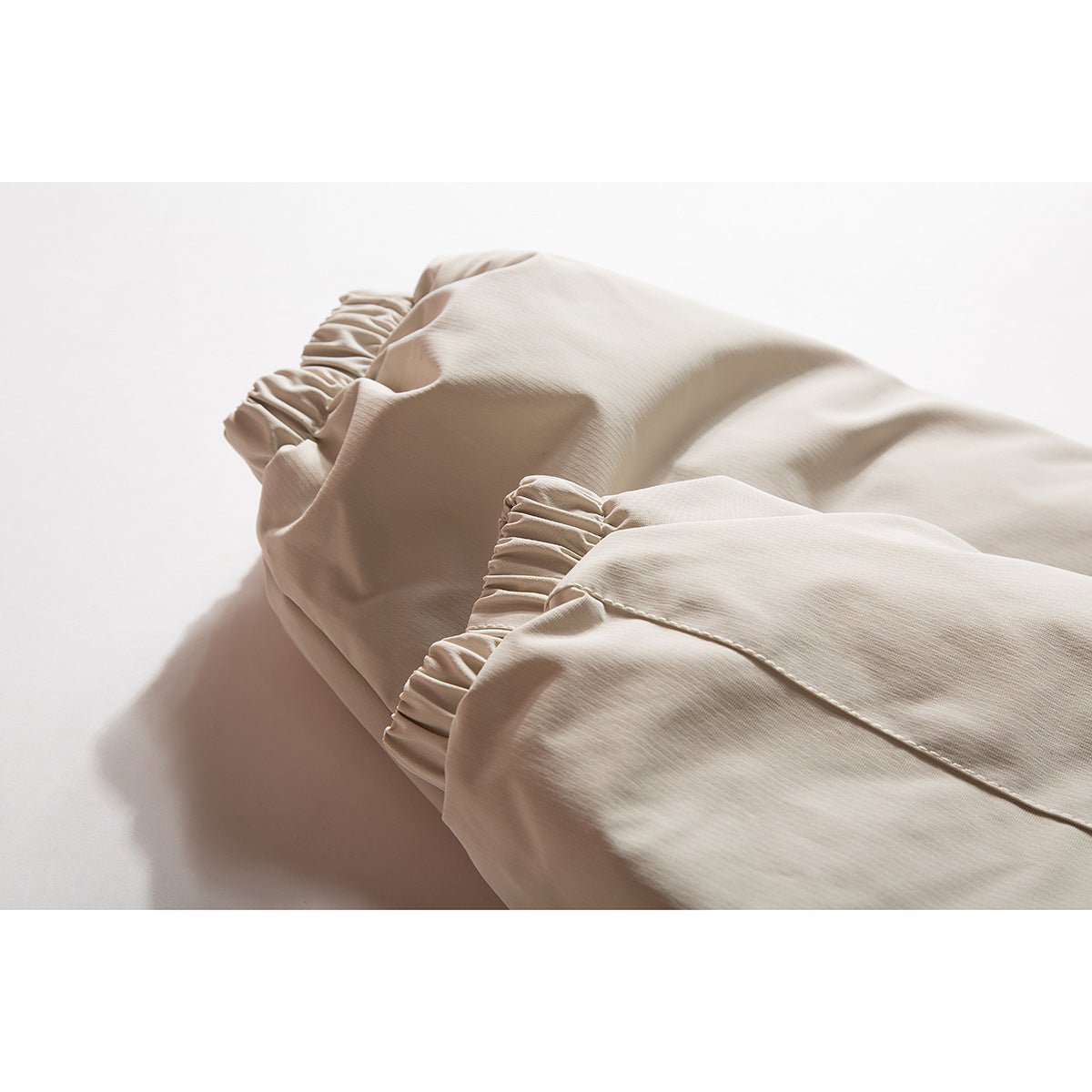 Close-up of the beige jacket's gathered elastic cuffs and sleeve fabric.