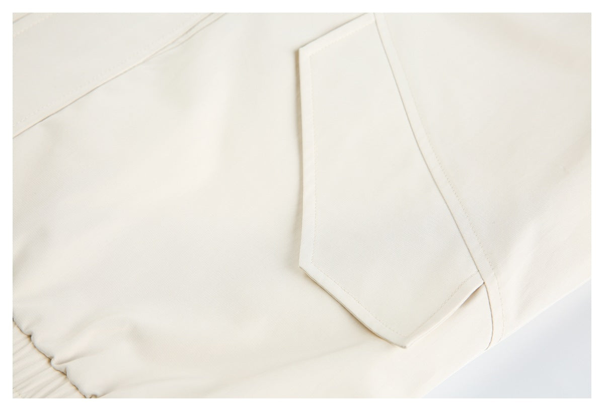 Close-up of a stitched flap pocket on a cream garment.