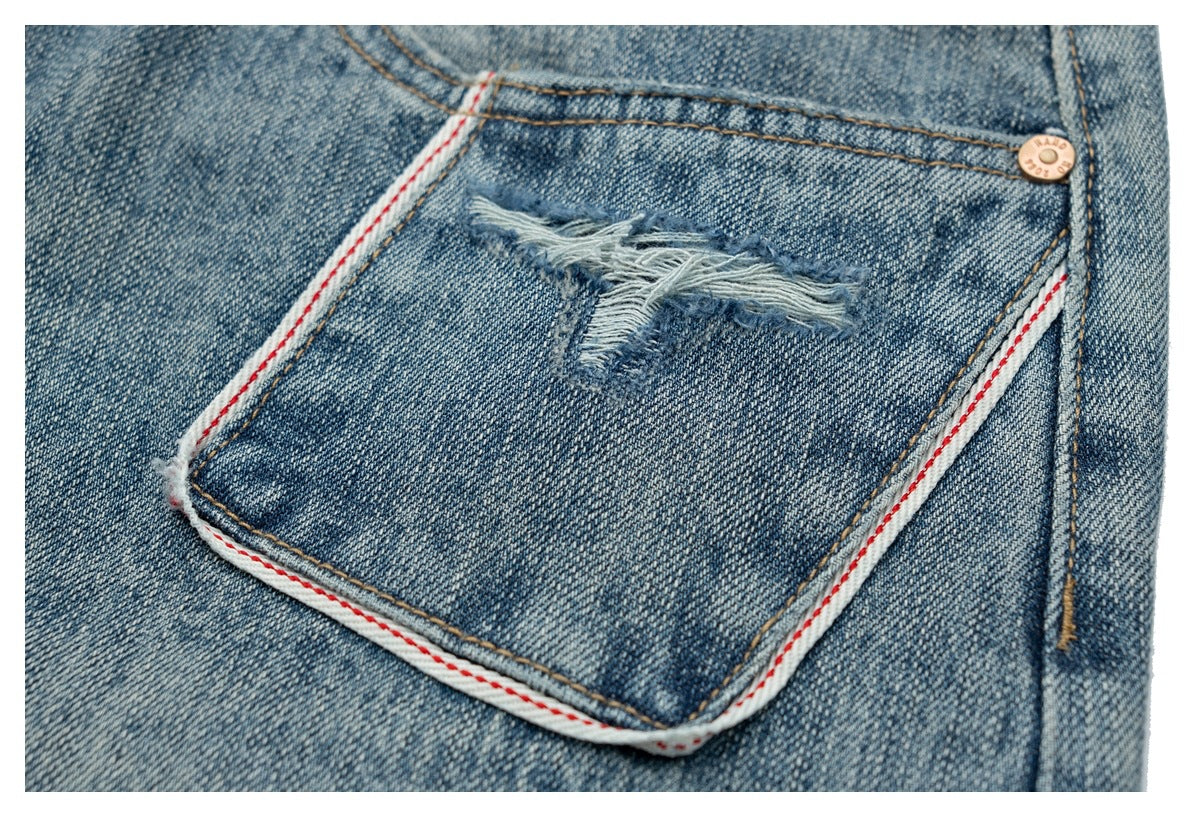 Close-up of a back jeans pocket with a frayed tear and red-and-white trim along the pocket edge.