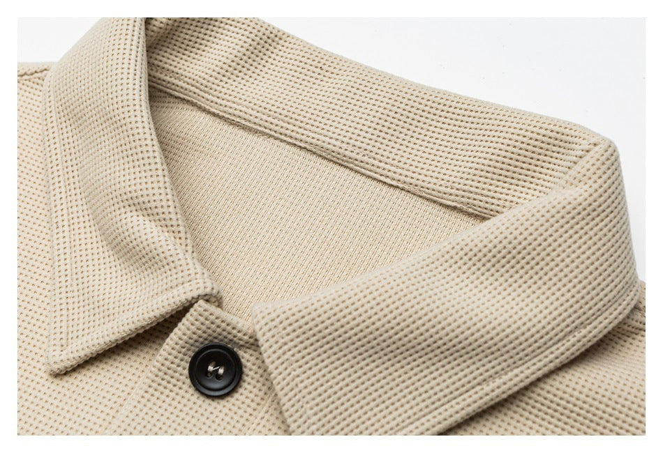 Close-up of the beige knit jacket's wide collar and a black button.