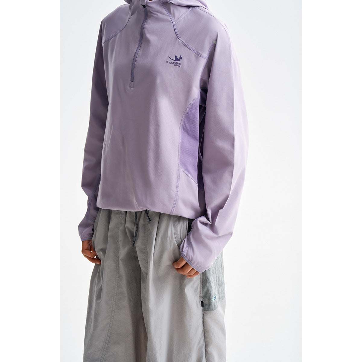 Close view of a person wearing a light lavender hooded pullover with a short zipper and gray shorts.