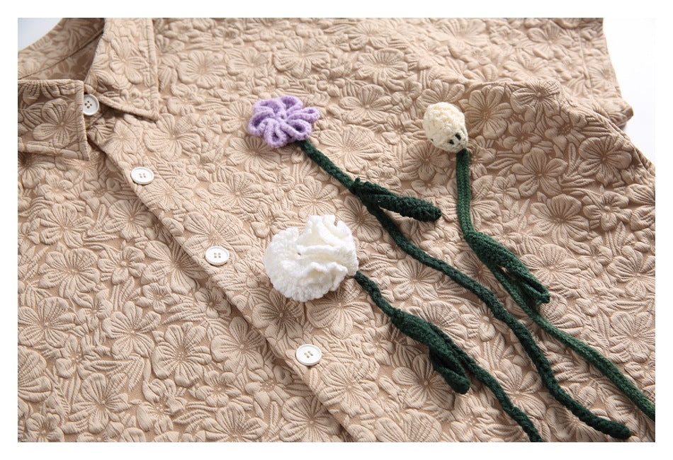Beige button-front shirt with raised floral texture and crocheted flower accents, shown flat.