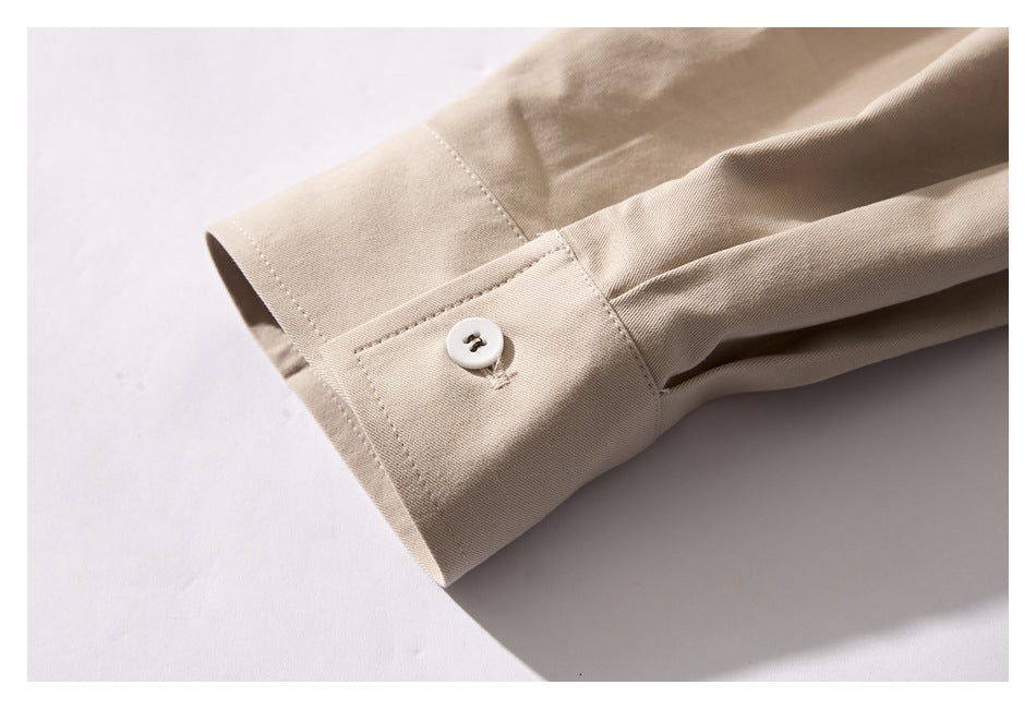 Close-up of a beige shirt cuff with a white button and neat stitching.