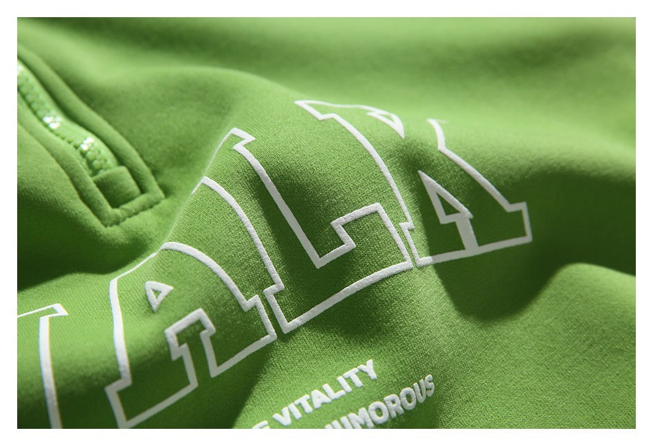 Close-up of raised white lettering and smaller text printed on the green hoodie.