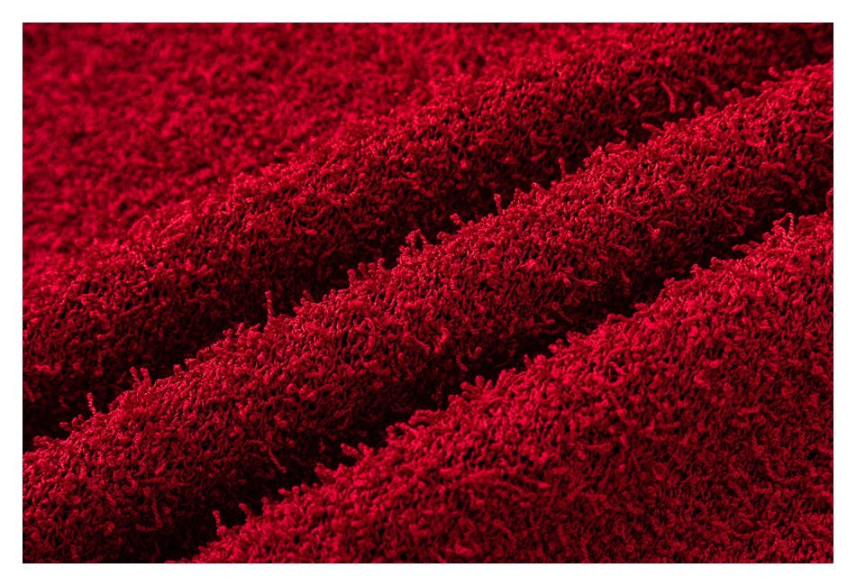 Macro view of deep red fuzzy knit fabric, highlighting its dense, raised loop texture.