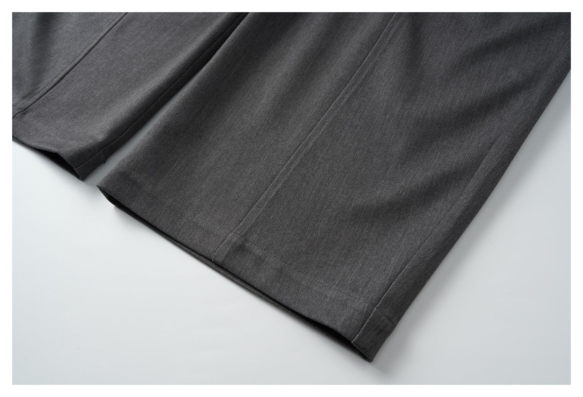 Close-up of the straight legs and stitched hems of charcoal trousers.