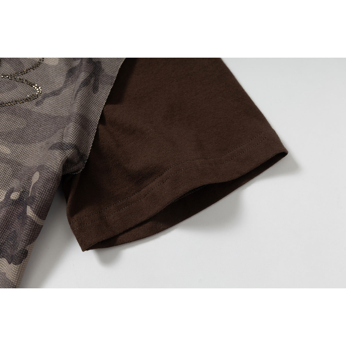 Close-up of the dark brown short sleeve beside the gray-brown camouflage body of the shirt.