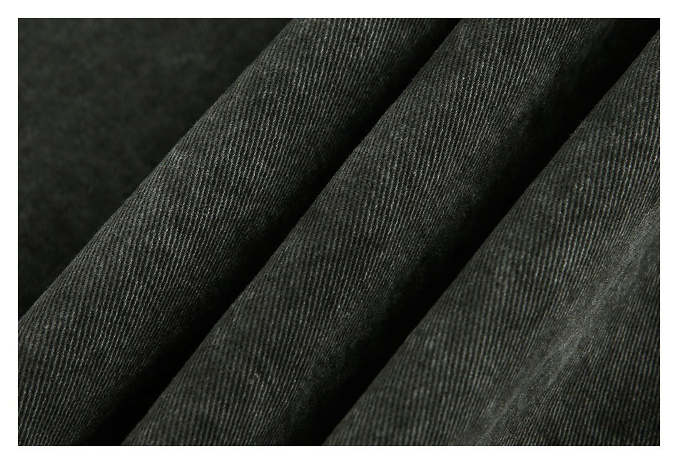 Close-up of dark charcoal fabric arranged in folds, showing its fine diagonal weave.