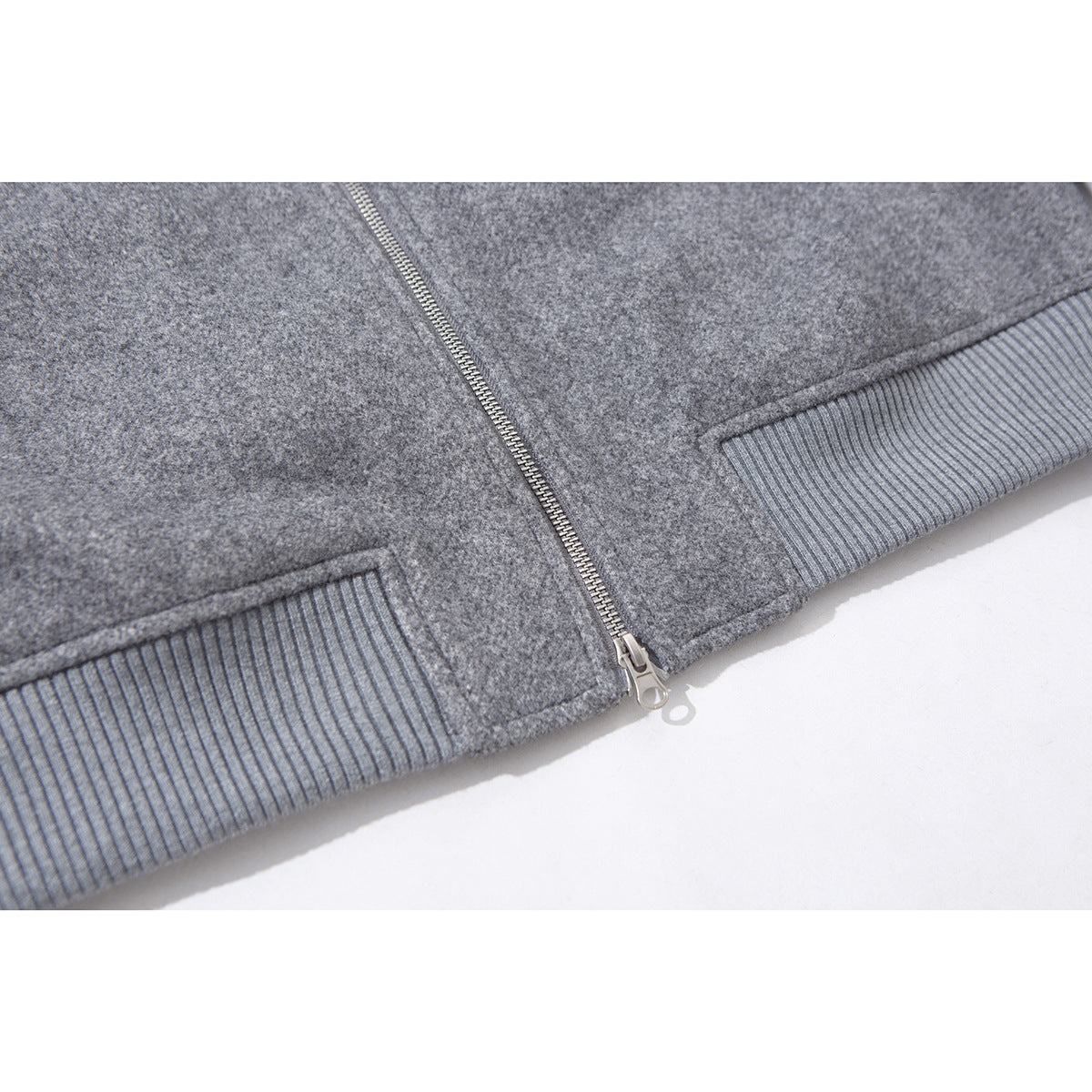 Close-up of the gray jacket's front zipper and ribbed knit hem.