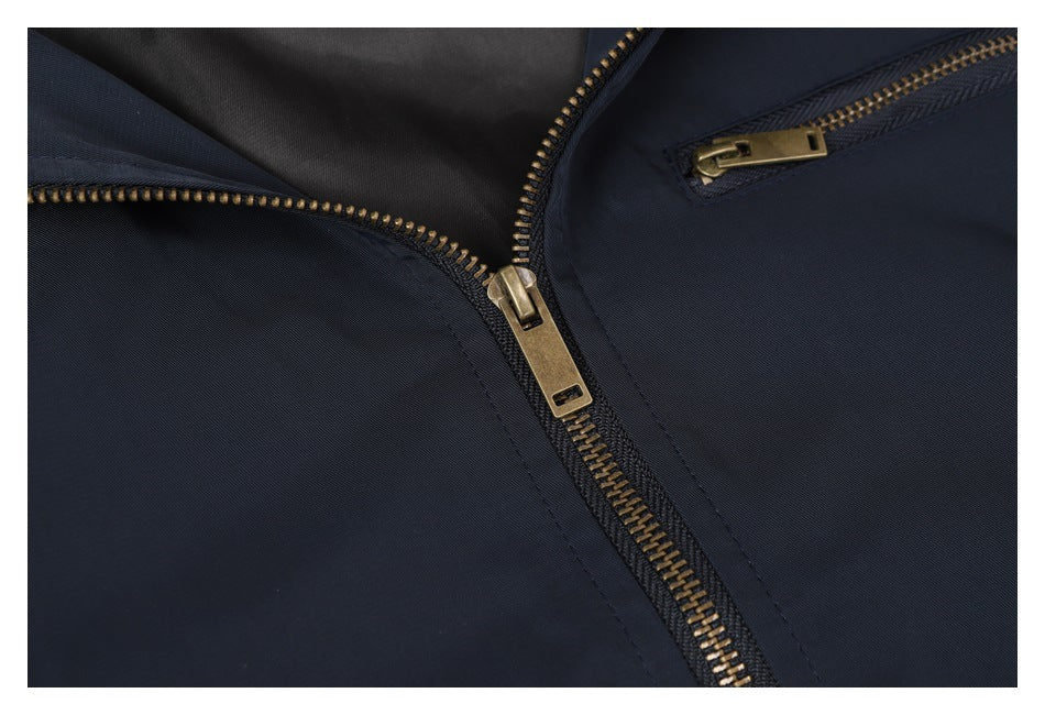 Close-up of the navy jacket's brass-tone main zipper and chest pocket zipper.