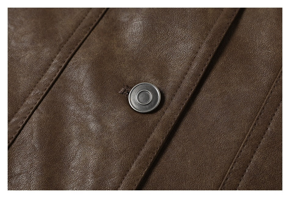 Extreme close-up of a round metal snap on a dark brown jacket, showing its textured surface and stitching.
