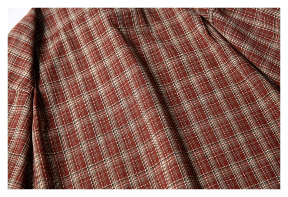 Close-up of draped reddish-brown plaid fabric with thin cream and dark intersecting stripes.