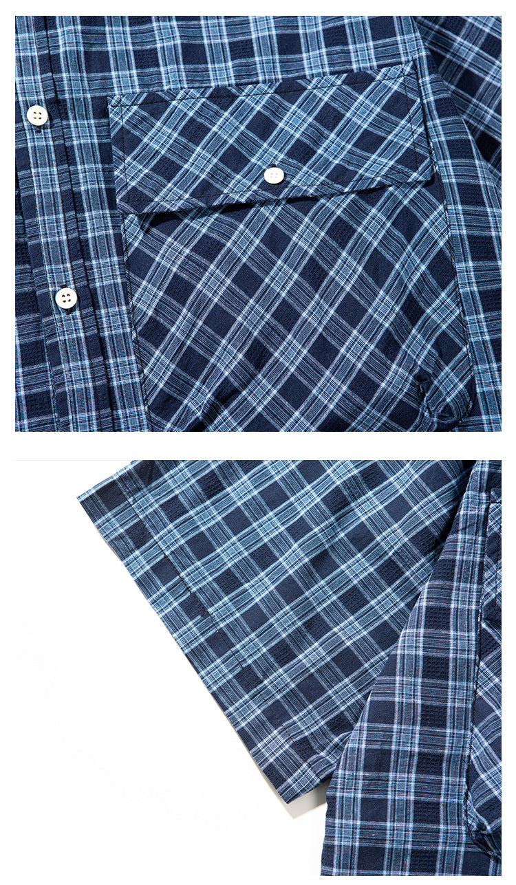 Close-up of a navy blue plaid shirt showing a buttoned chest pocket, white buttons, and sleeve.