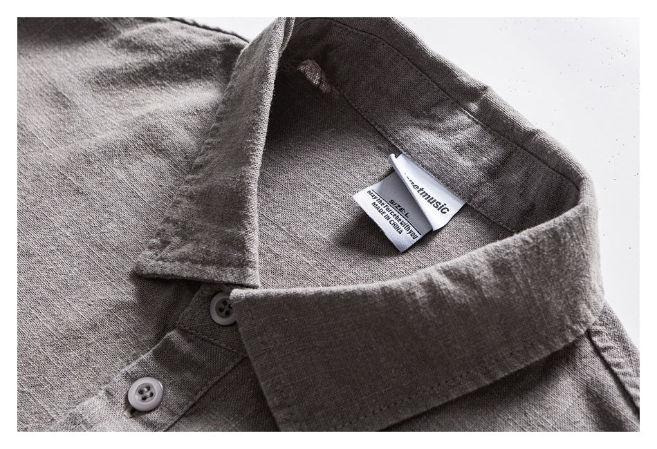 Close-up of a gray shirt's pointed collar, buttons, and sewn-in neck label.