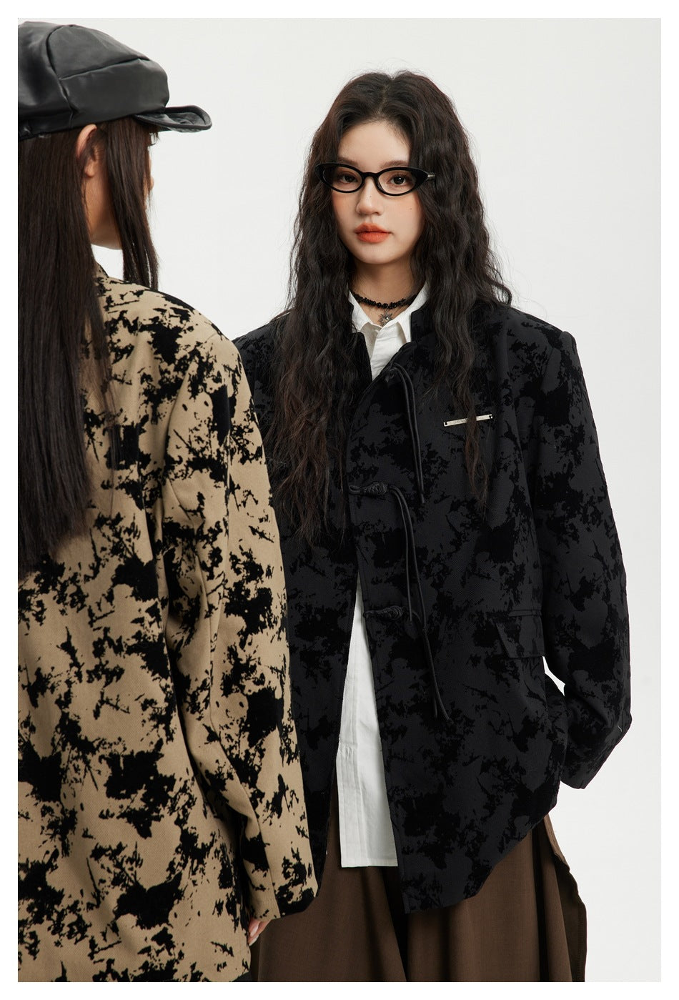 Close view of a model wearing the black abstract-print jacket with frog closures and flap pockets; taupe version partly