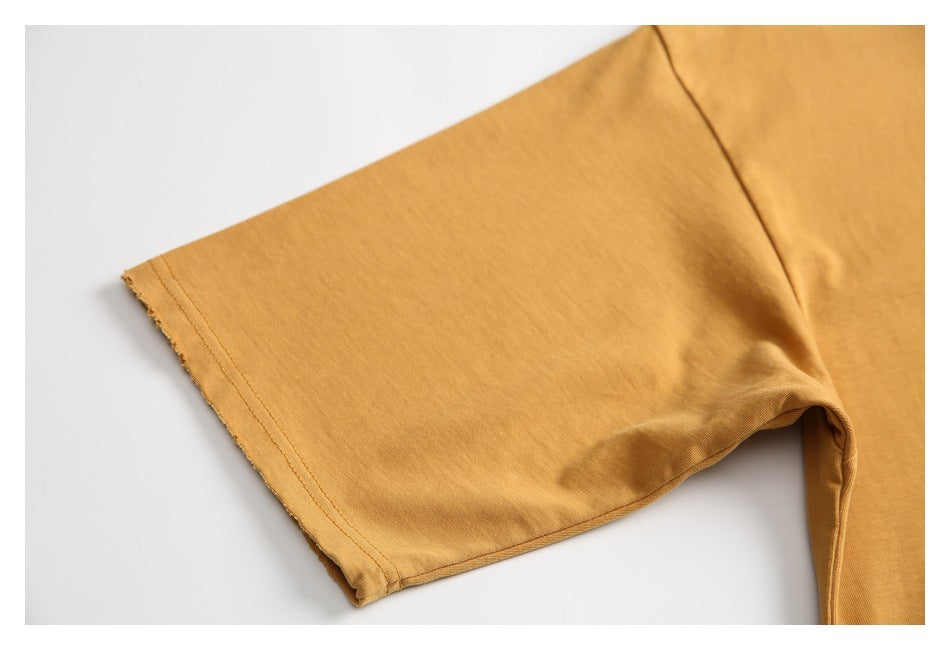 Close-up of the ochre T-shirt sleeve, showing the hem stitching and shoulder seam.