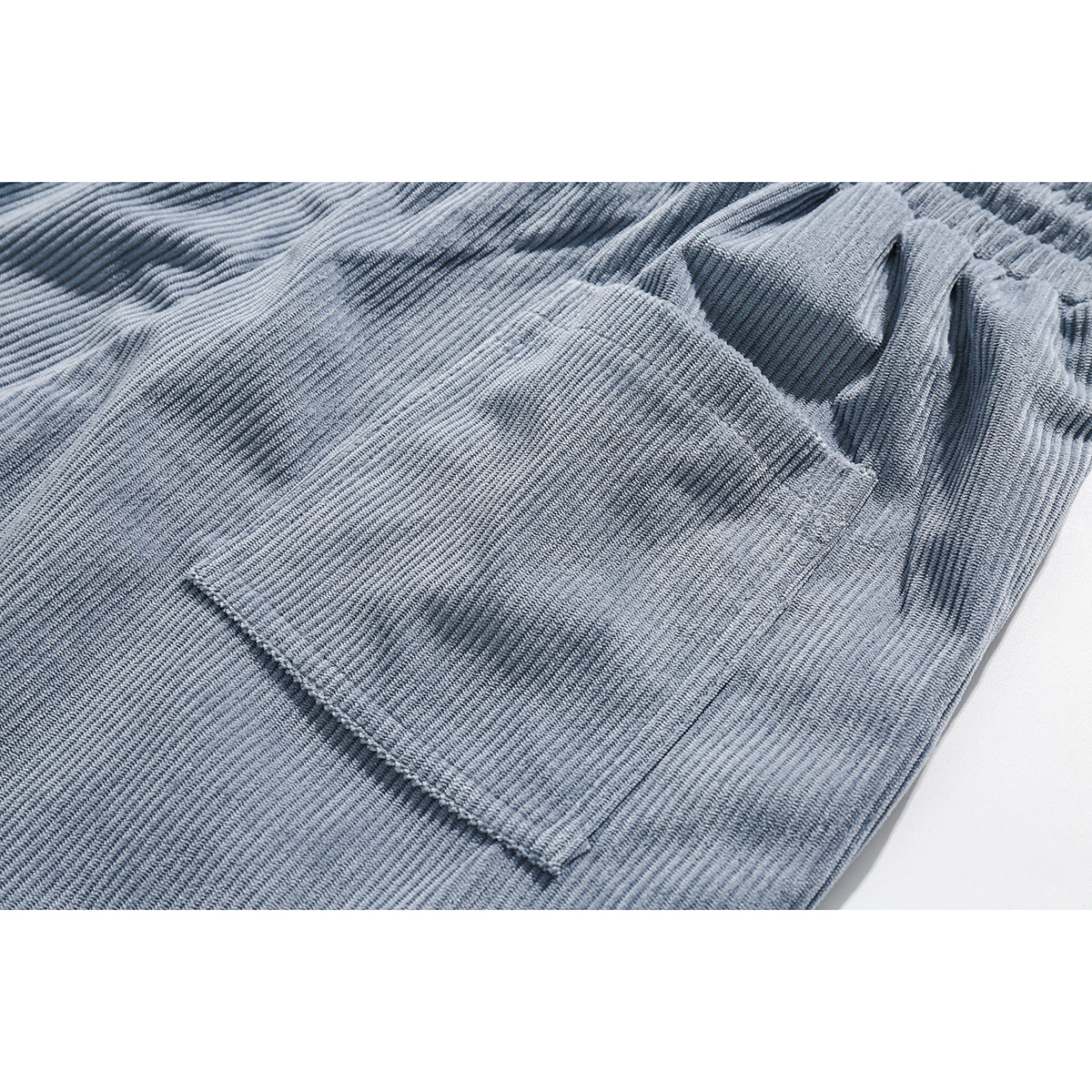 Close-up of light blue corduroy shorts showing a stitched side pocket and elastic waistband.