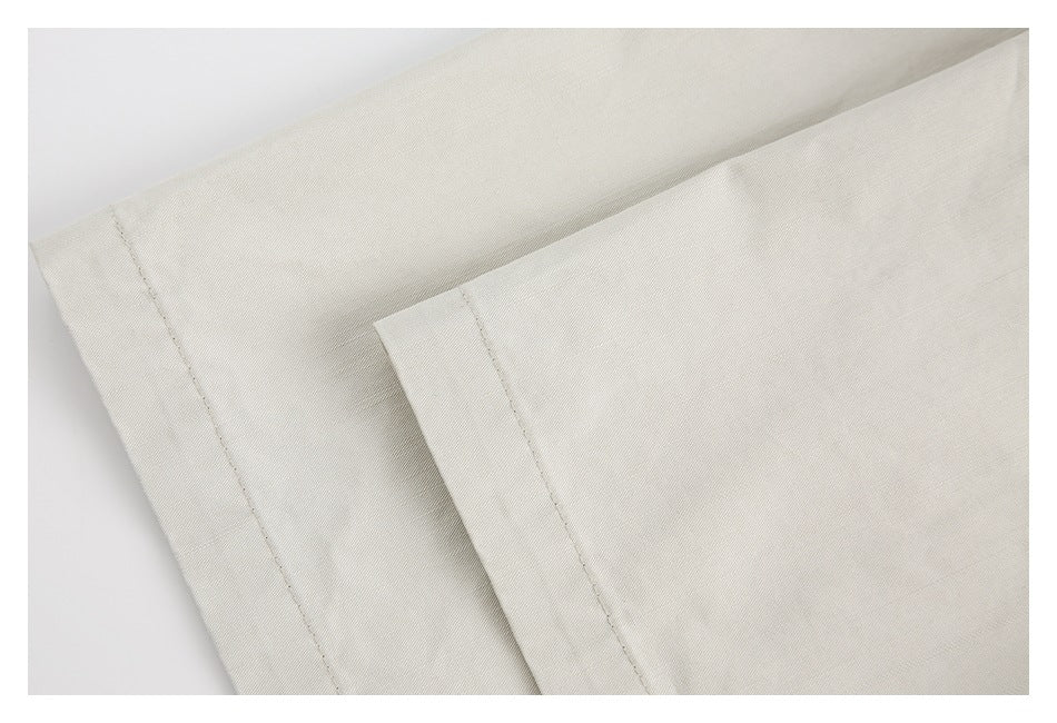 Close-up of overlapping off-white garment edges with stitched hems.