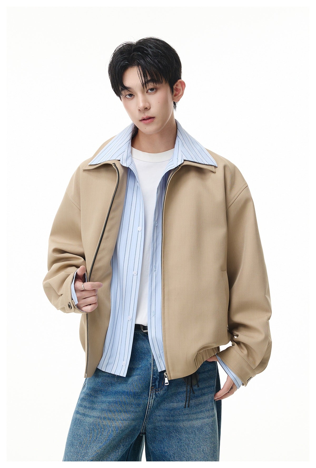 Model wearing an open beige jacket over a light blue vertically striped shirt and white tee.