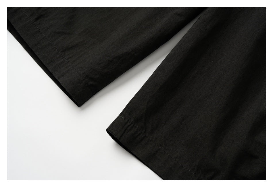Close-up of the stitched hems on the legs of black pants.