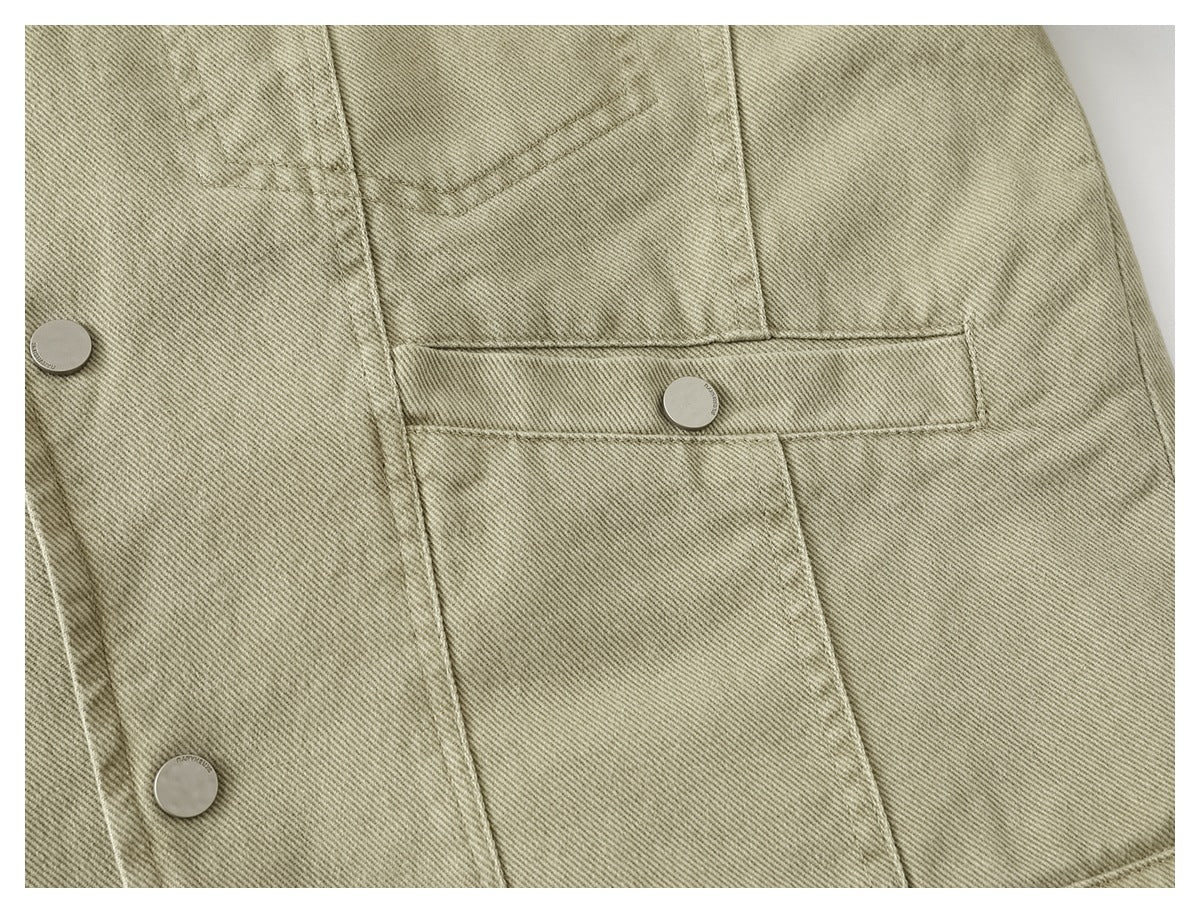 Close-up of a muted khaki jacket front with a flap pocket, diagonal twill texture, and silver snap buttons.