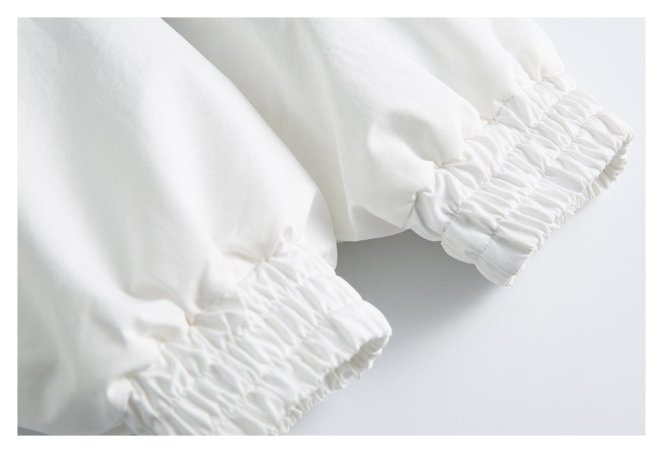 Close-up of two white garment cuffs with gathered elastic edges.