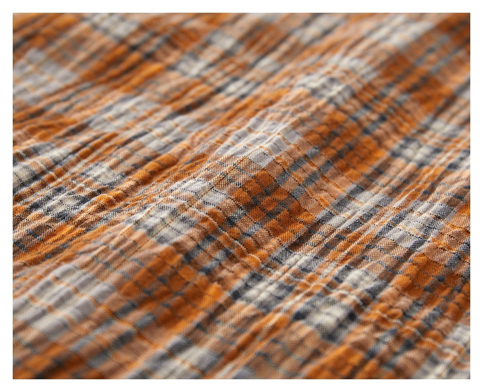 Macro view of the orange, gray, and cream plaid fabric texture.