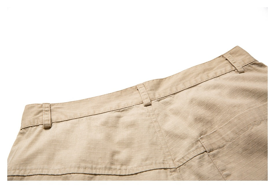 Close-up of tan trousers showing the waistband, belt loops, seams, and subtle horizontal fabric texture.