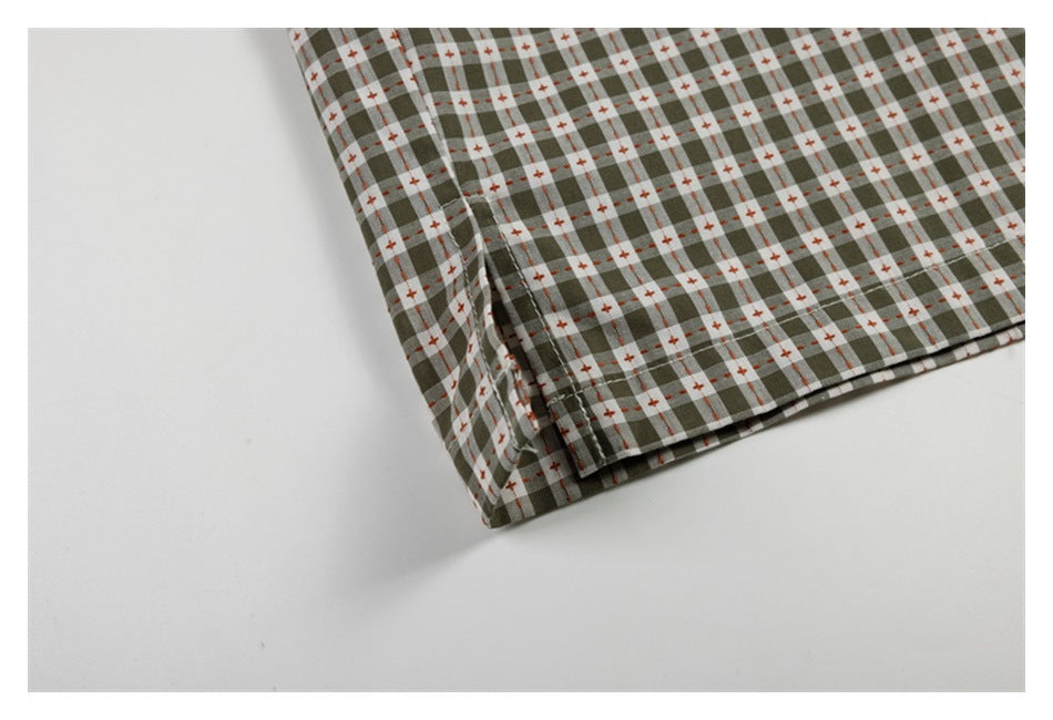 Close-up of the folded lower edge of a gray-green check shirt on a white background.