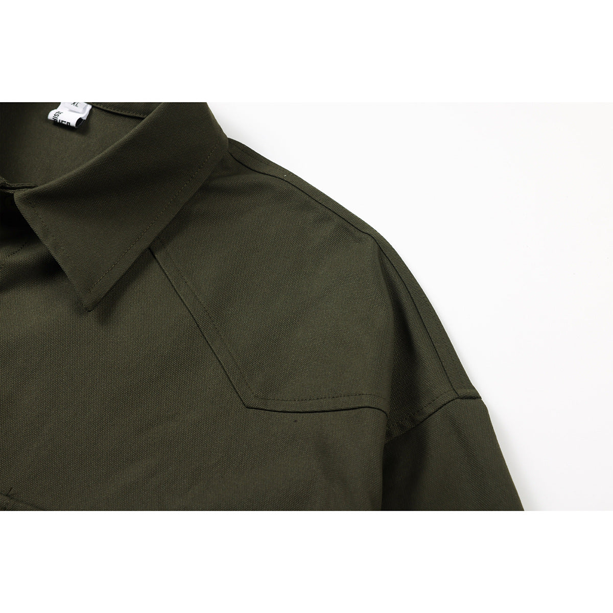 Close-up of a dark olive shirt collar and stitched shoulder yoke.