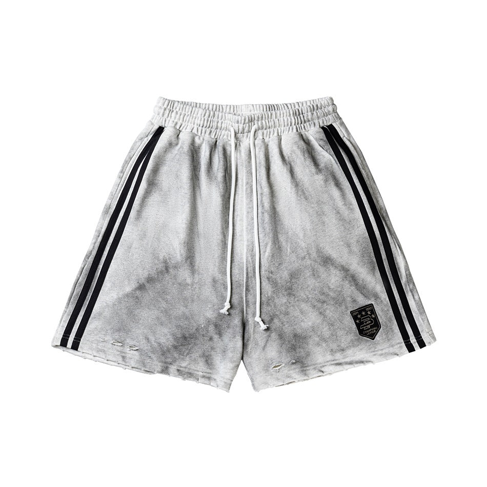 Distressed gray drawstring shorts with black double side stripes, shield patch and frayed hems, flat lay front view