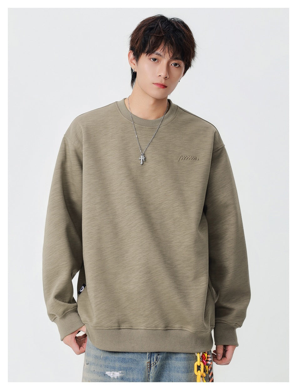 Front view of a model wearing a taupe oversized crewneck sweatshirt with ribbed cuffs, hem, and a small chest logo.
