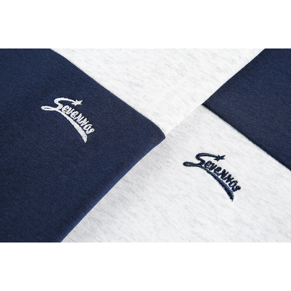 Close-up of small embroidered script logos on gray and navy shirt fabric.