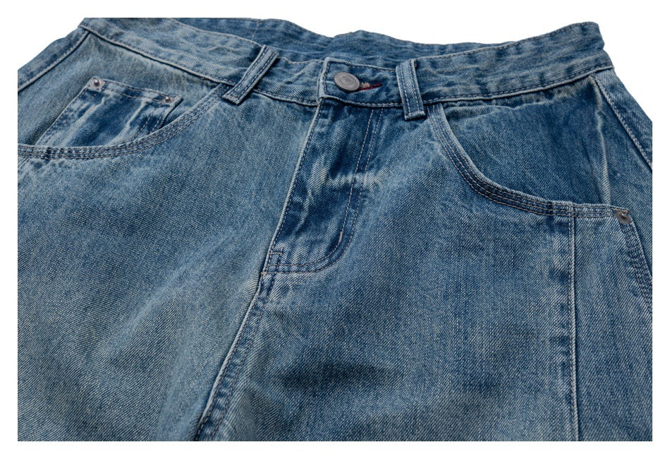 Close-up of the button, fly, belt loops and front pockets on faded blue jeans.