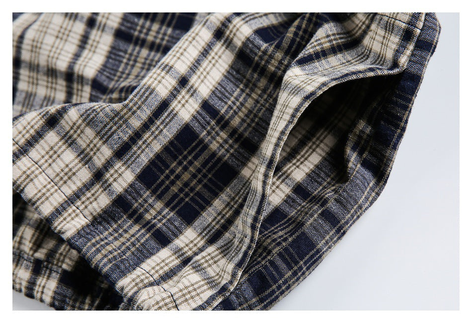 Close-up of the plaid jacket's curved pocket opening and stitched edge.