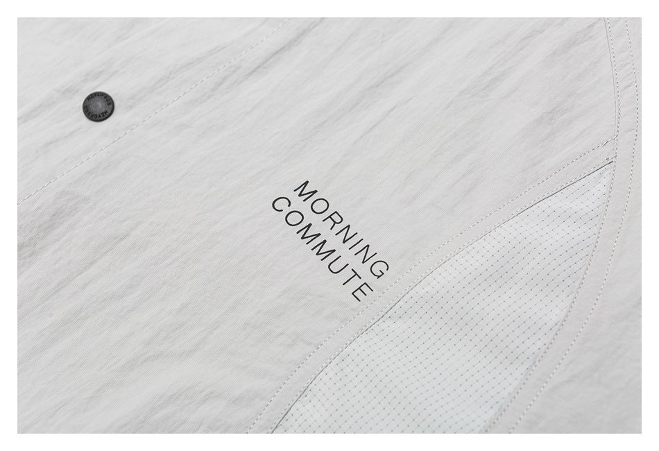 Close-up of the light gray shirt showing its “MORNING COMMUTE” print, seam, and button.