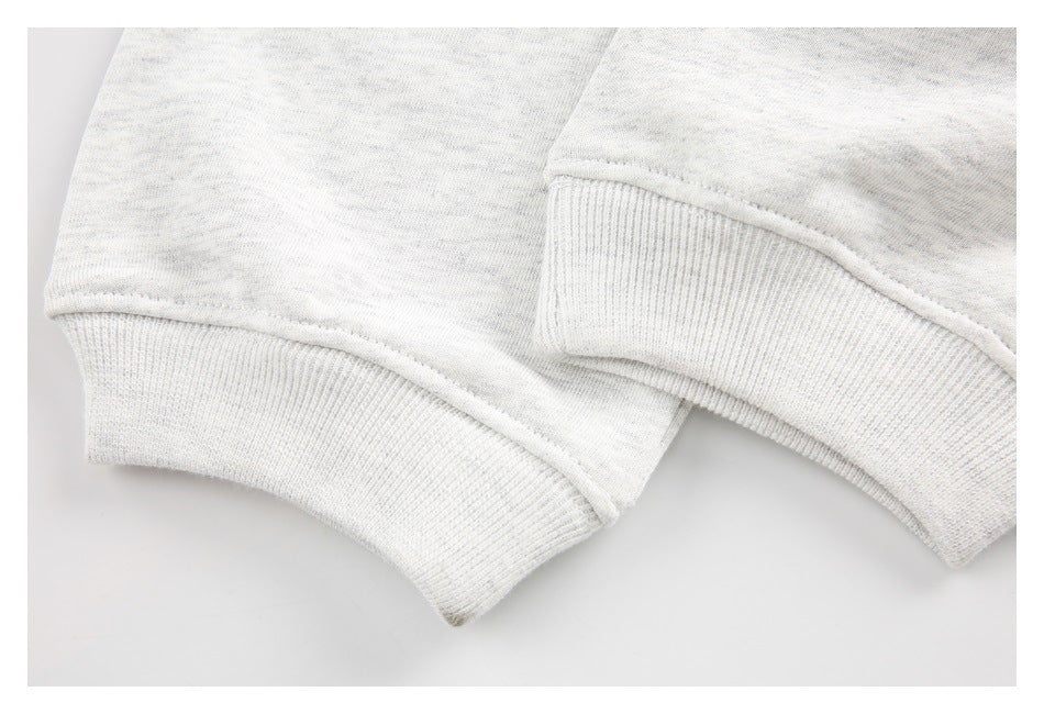 Close-up of ribbed cuffs and seams on light gray heathered sweatshirt fabric.