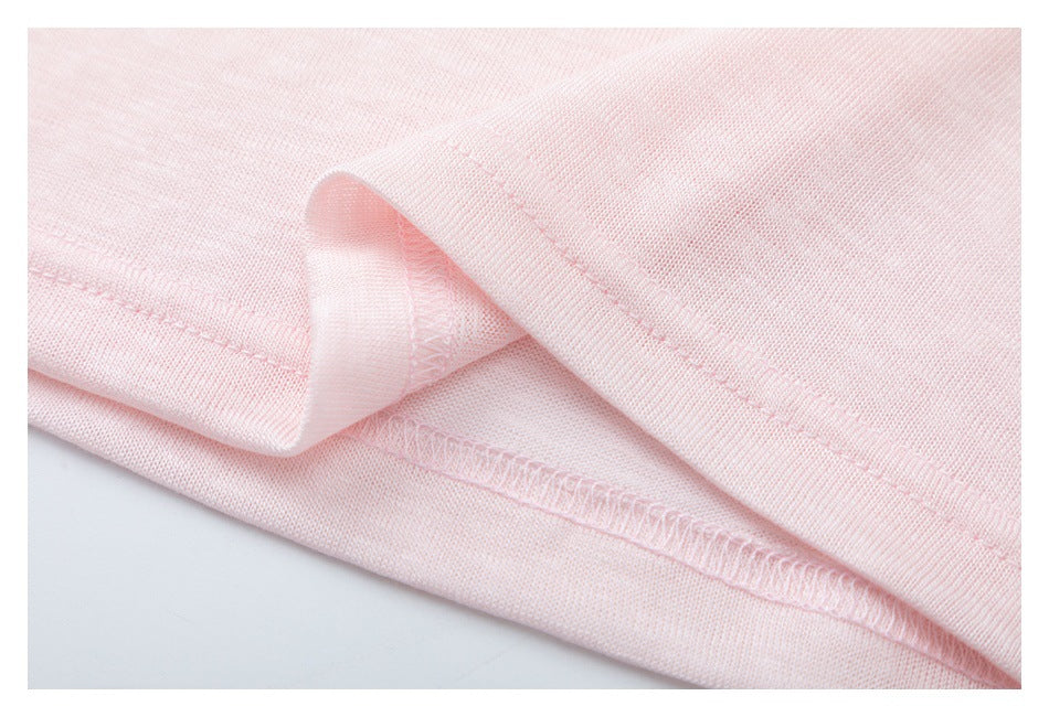 Close-up of pale pink knit fabric showing a folded hem and overlocked seam.