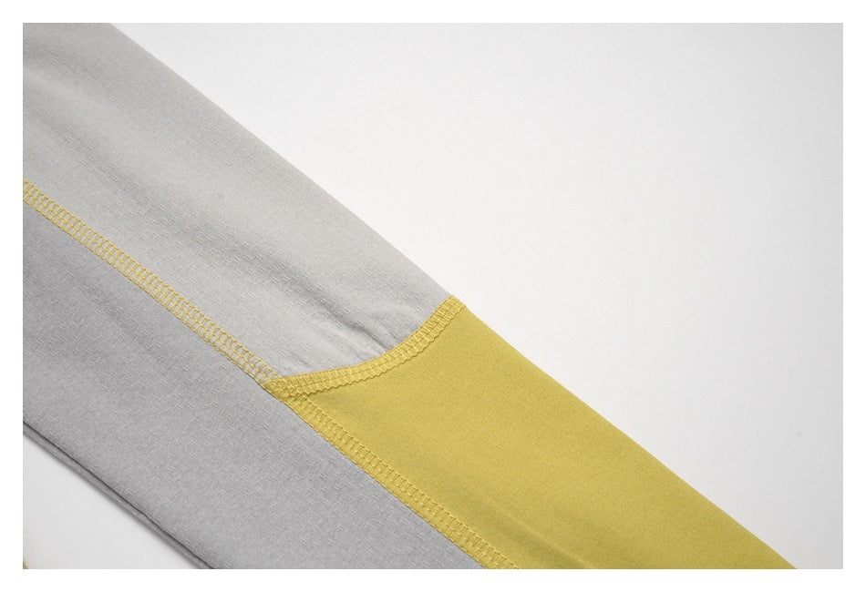 Close-up of a mustard-yellow panel and contrasting overlock seams on a gray top.