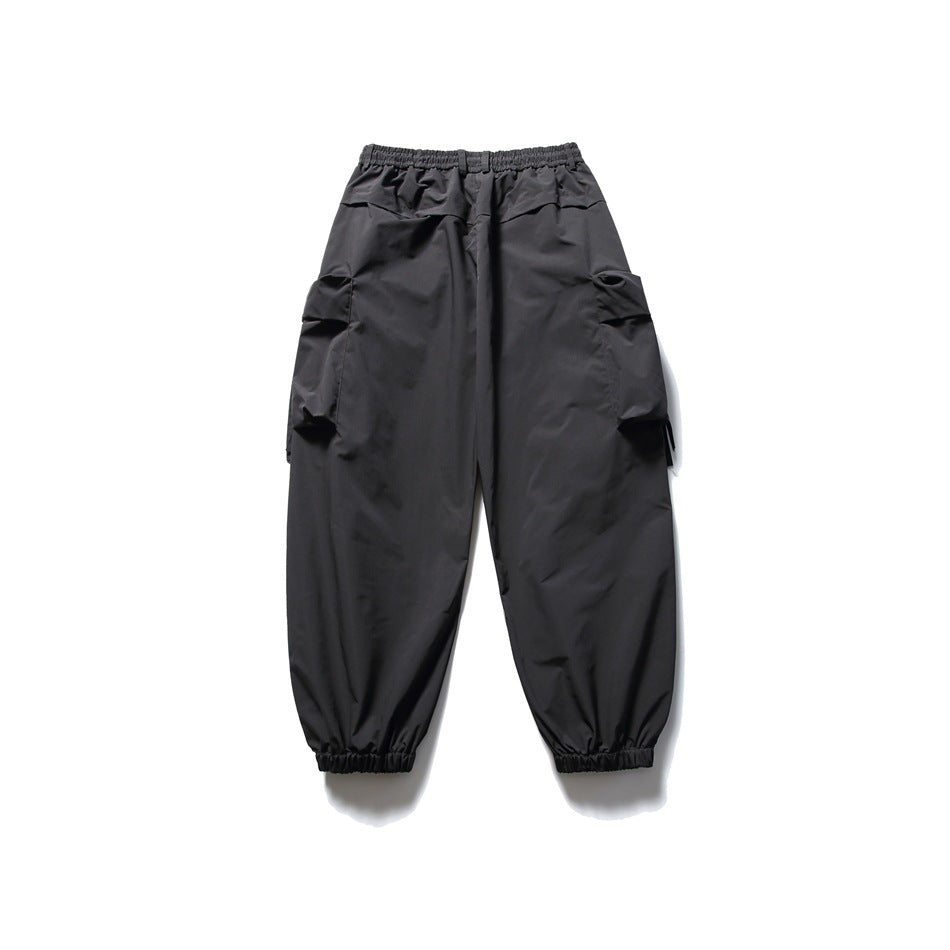 Black loose-fit cargo pants with an elastic waist, large side pockets, and gathered ankle cuffs, shown flat.