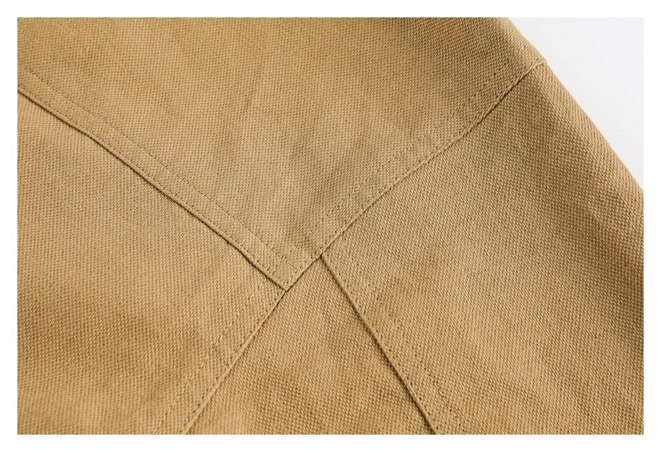Close-up of tan garment fabric with intersecting stitched seams.
